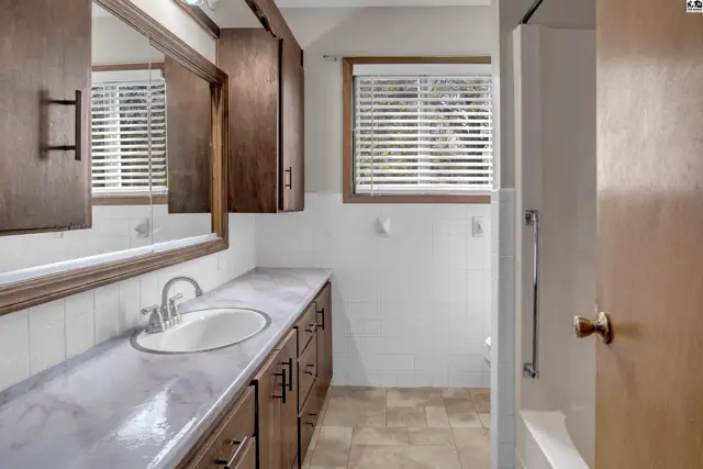 Spacious bathroom with a long vanity, marble-look countertop, and dark wood cabinets.