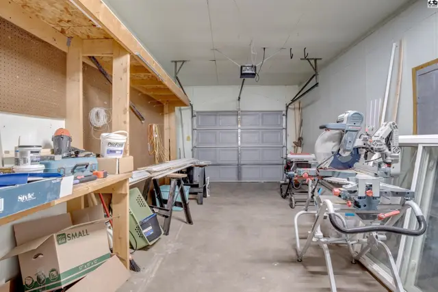 Workshop with tools, lumber, and storage shelves, featuring a large garage door.