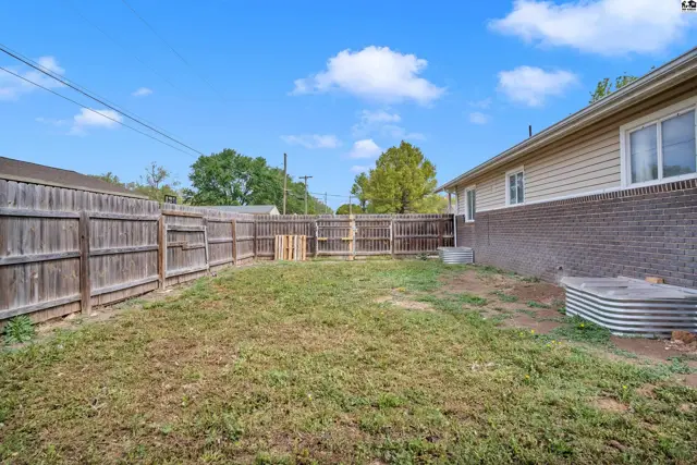 Spacious backyard with a wooden fence, grass, and metal water troughs.