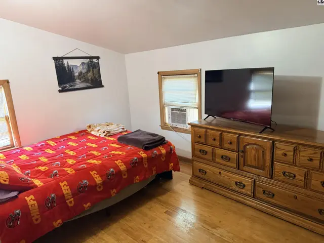 This bedroom features a queen-size bed, a wooden dresser, and a flat-screen television.