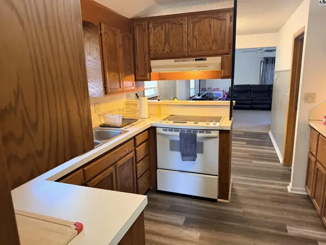 This kitchen features wood cabinetry, a white stove, and a laminate floor.