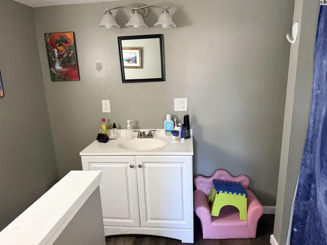 This bathroom features a white vanity with a cultured marble countertop and a large mirror.