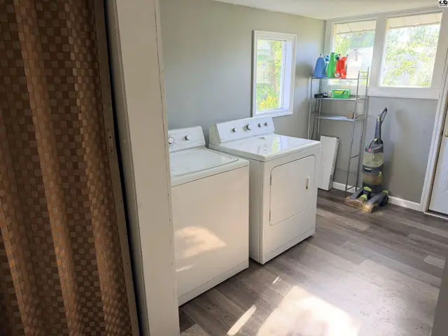 This laundry room features a washer, dryer, shelving, and a vacuum cleaner.