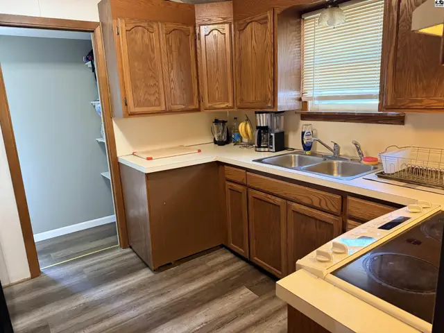 Kitchen features wood cabinets, laminate countertops, and a double sink.