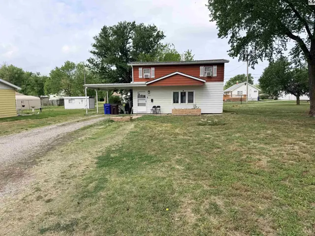 White and brown siding house with a covered carport and gravel driveway.
