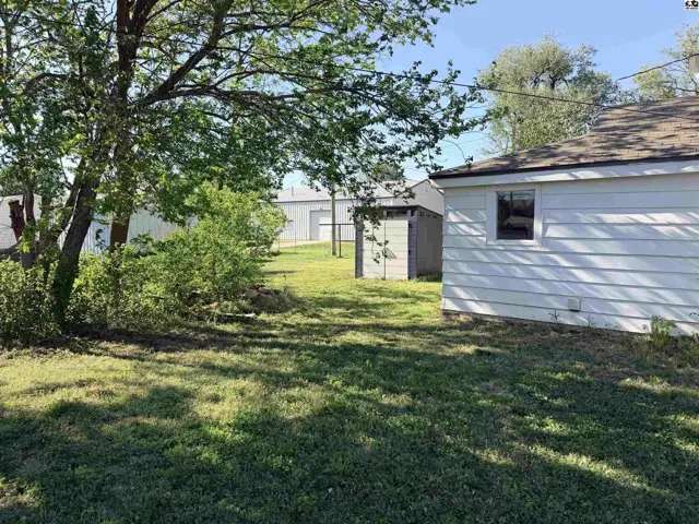 White siding house with a grassy yard and a detached shed.