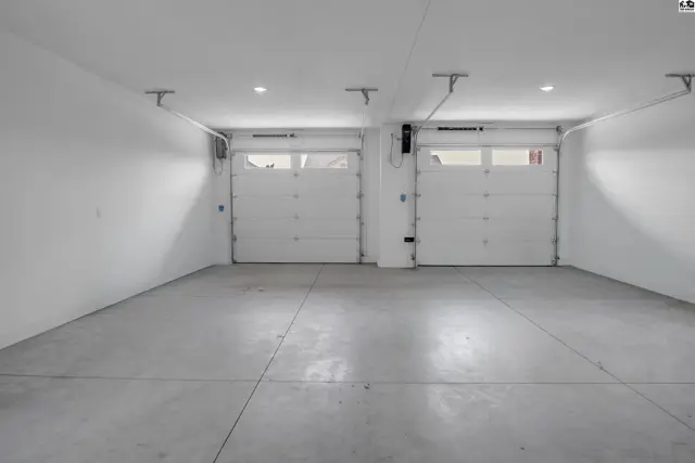 Spacious garage with two overhead doors and a smooth concrete floor.