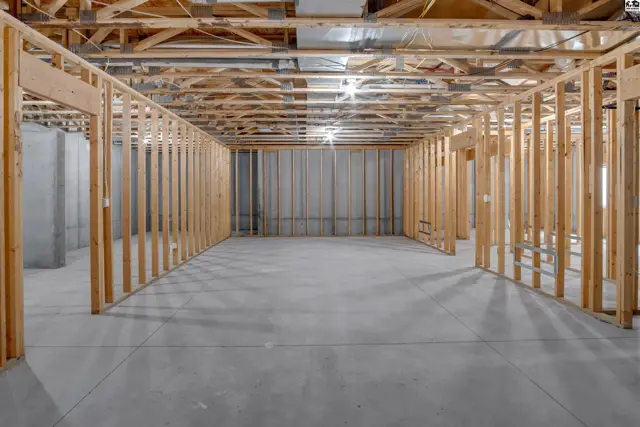 Unfinished basement with concrete floor and framed walls.