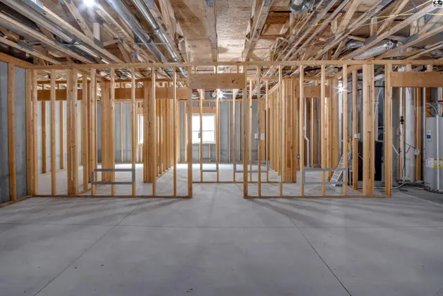 Unfinished basement with concrete floor and exposed wooden framing.