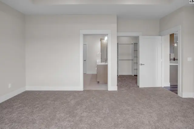 Spacious room with plush carpet, leading to a closet and bathroom.