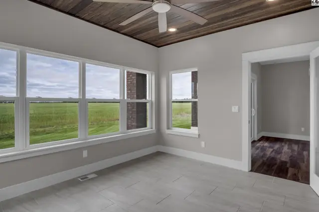 Sunlit room with large windows, wood-paneled ceiling, and light-colored tile flooring.