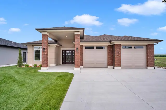 This modern home features a stucco exterior, brick accents, and a three-car garage.