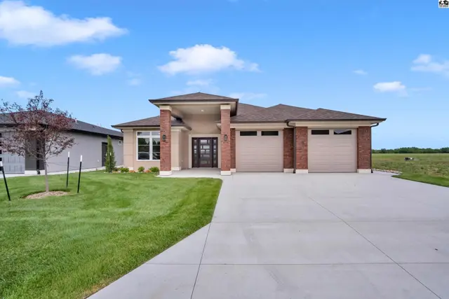 Modern brick home features a three-car garage and manicured lawn.
