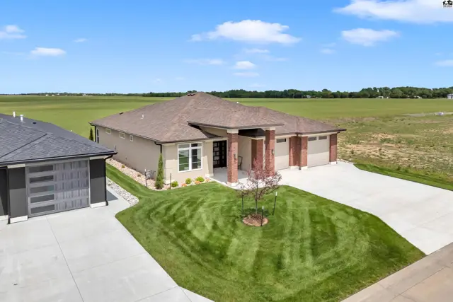 Modern home with attached garage, manicured lawn, and brick accents.