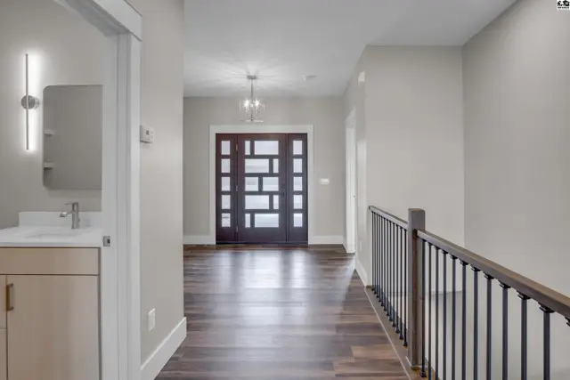 Modern entryway with dark wood flooring, a glass-paneled door, and a contemporary vanity.