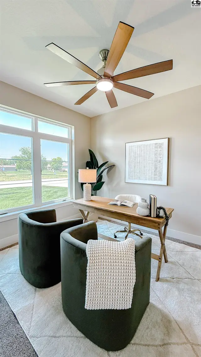 This room features a large wooden desk, two green chairs, and a ceiling fan.