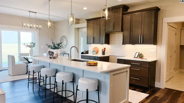 Spacious kitchen features dark wood cabinetry, white subway tile backsplash, and a large island with seating.