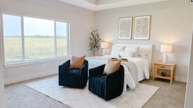 Spacious bedroom features a king-size bed, two armchairs, and large windows.