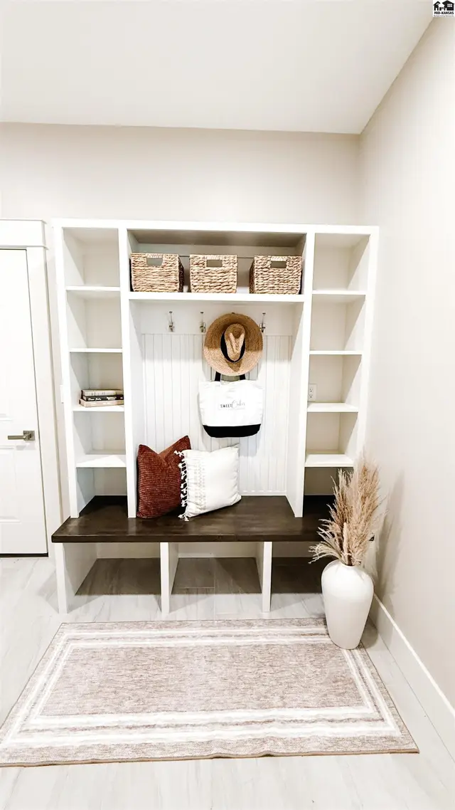 Built-in white shelving unit with a dark wood bench and woven baskets.
