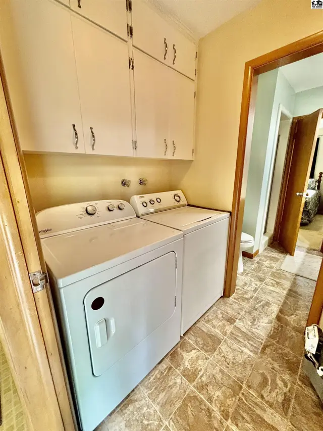 Laundry room with white washer and dryer, beige walls, and tiled floor.