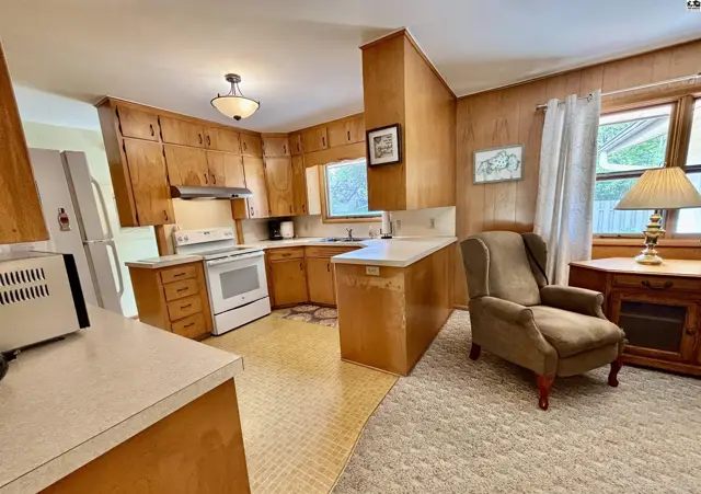 Warm wood cabinets and paneling define this cozy kitchen with a comfortable armchair.