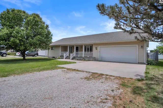 Exterior of a beige ranch home with a covered porch, white railings, and a large attached garage.