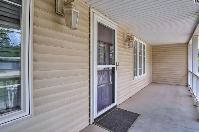 Covered porch with beige siding, white trim, and a screen door.