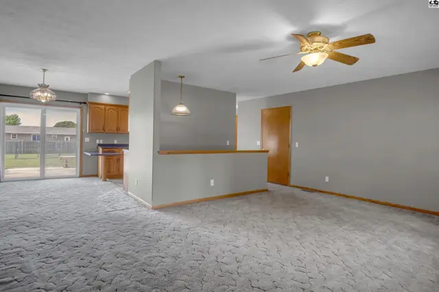 Spacious living area with plush carpet, breakfast bar, and access to a backyard patio.