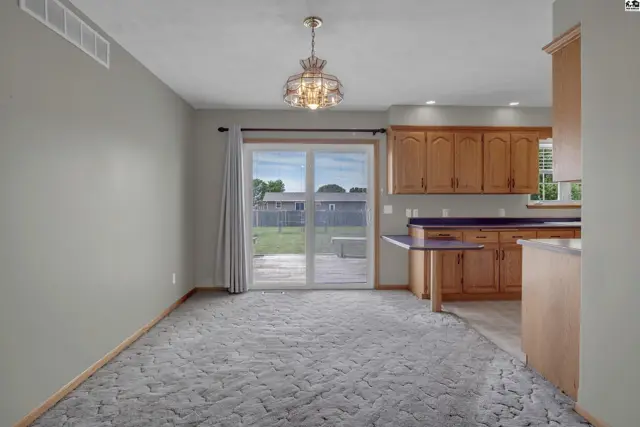 Dining area with plush carpet opens to a kitchen with oak cabinets and a sliding glass door to the backyard.