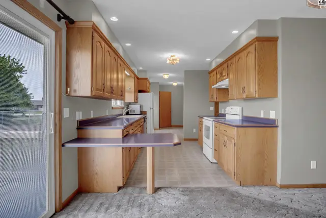 Spacious kitchen with light wood cabinets, purple countertops, and a built-in breakfast bar.