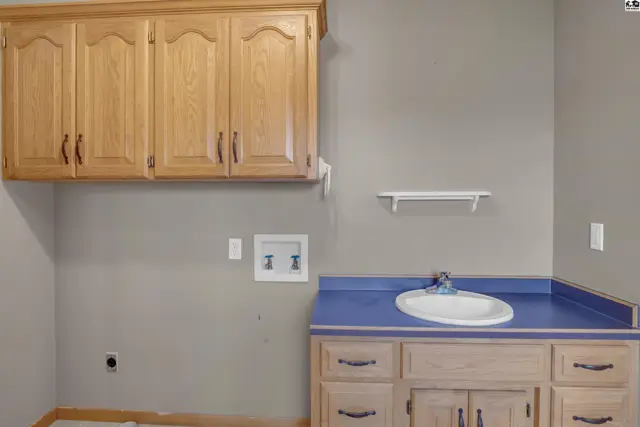 Laundry room with oak cabinets, blue countertop, and a utility sink.