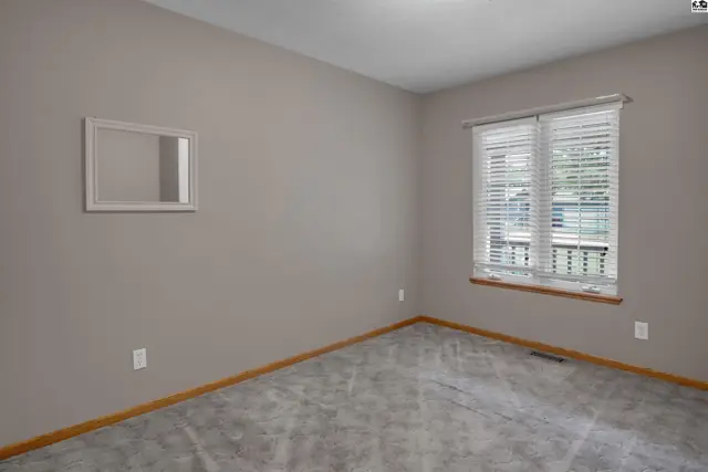 Empty room with gray carpet, neutral walls, and a window with blinds.