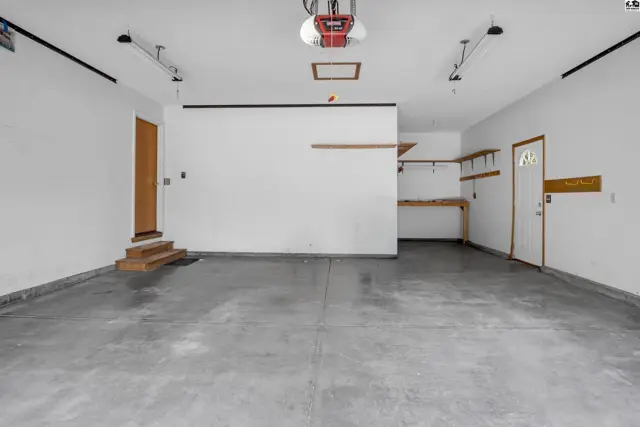 Spacious, clean garage with concrete floors, white walls, and built-in shelving.