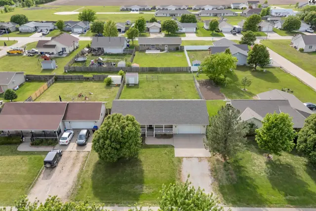 Aerial view of a suburban neighborhood with a light-colored ranch-style home and manicured lawns.