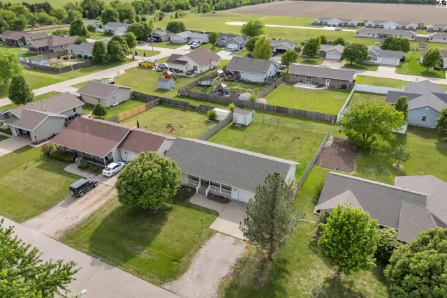 Aerial view of a suburban neighborhood with single-family homes, manicured lawns, and mature trees.