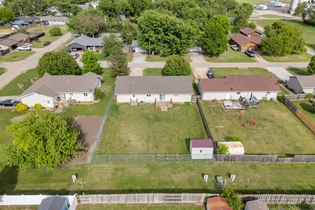 Aerial view of suburban homes with fenced backyards, green lawns, and mature trees.