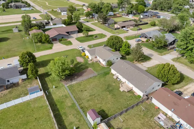 Aerial view of a suburban neighborhood with a house, large yard, and detached garage.