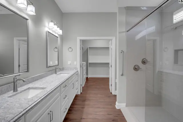 Spacious bathroom features a double vanity, walk-in closet, and glass-enclosed shower.