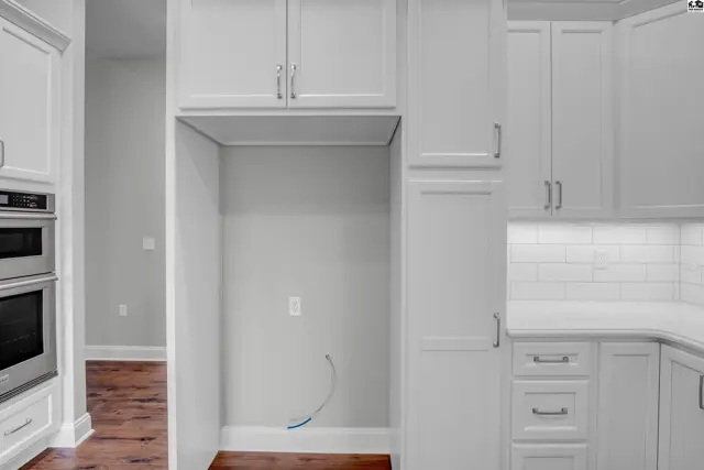 White cabinetry with stainless steel appliances and a built-in microwave is featured.
