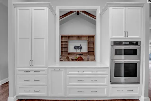 White cabinetry with stainless steel appliances and a large pass-through window.