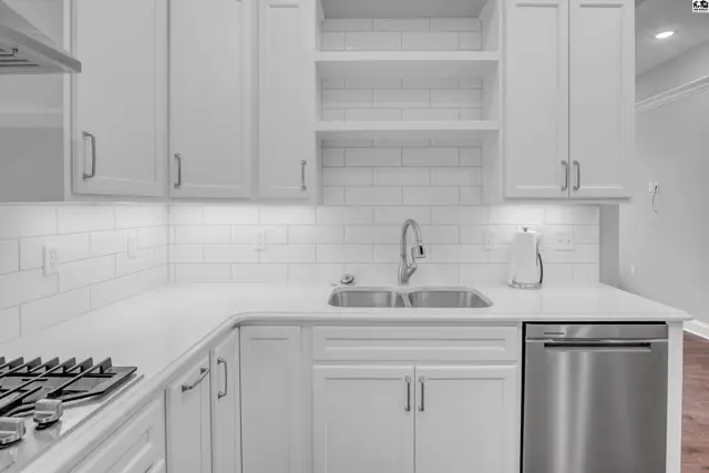 White cabinetry, subway tile backsplash, and stainless steel appliances highlight this modern kitchen.