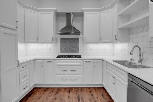 White cabinetry, subway tile backsplash, stainless steel appliances, and hardwood floors define this kitchen.