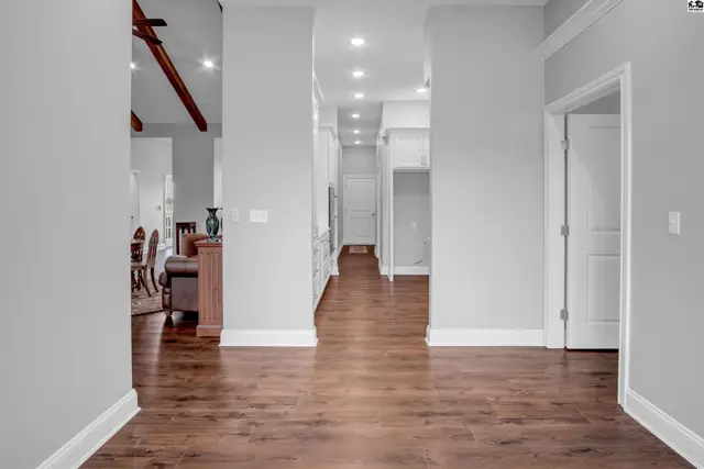 This hallway features hardwood floors, recessed lighting, and a view into an open living area.
