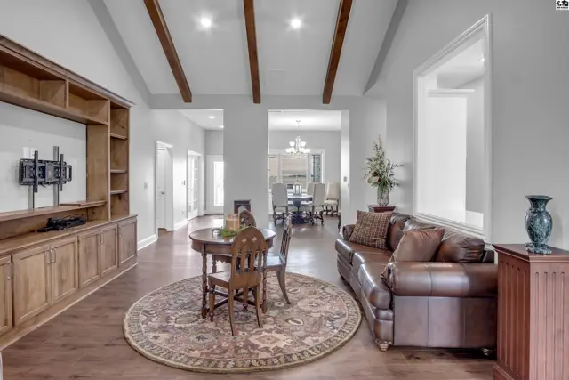 Vaulted ceiling with exposed beams above a living area with built-in shelving.