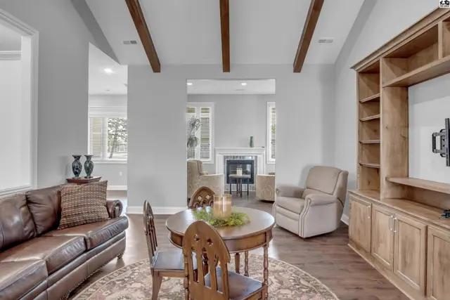 This living area features a leather sofa, a round dining table, and a built-in wooden entertainment center.