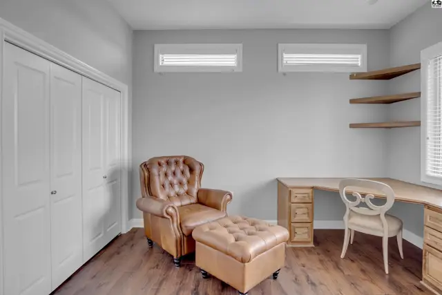 This room features a large closet, a desk with drawers, and a tufted leather chair with an ottoman.