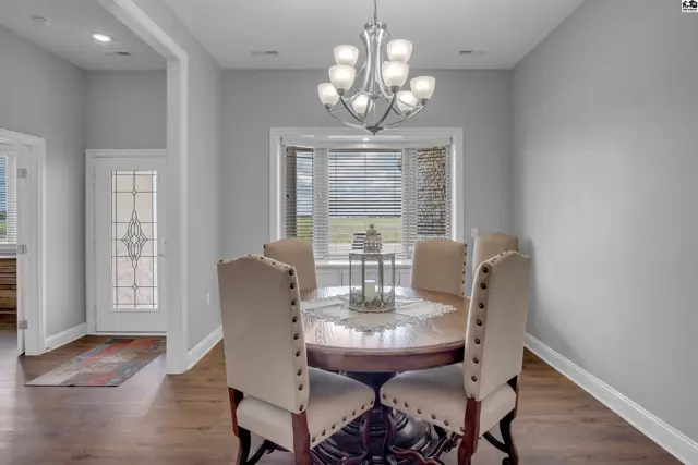 This dining room features a round wooden table, upholstered chairs, and a chandelier.