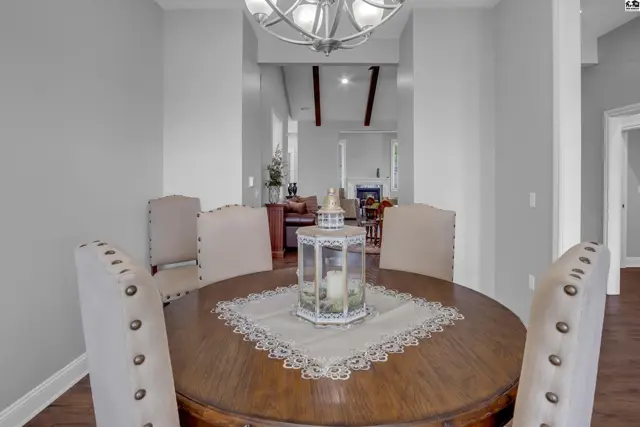 Round wooden dining table with upholstered chairs and a decorative lantern.