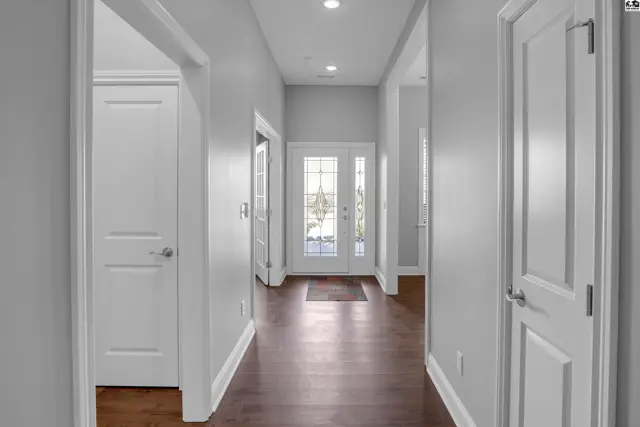This hallway features white doors, recessed lighting, and dark wood flooring.