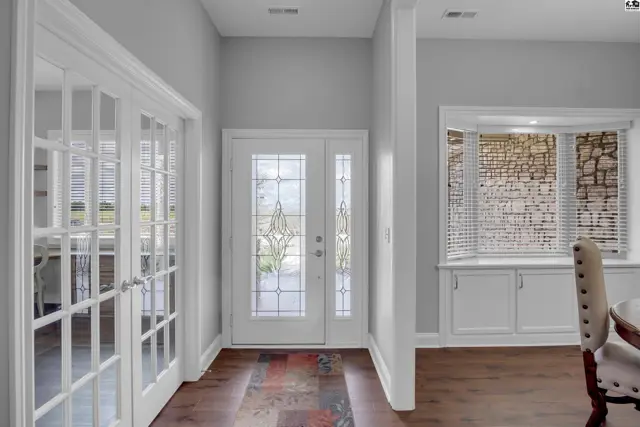Bright entryway features glass-paneled doors, a decorative transom window, and wood flooring.